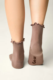 Brown socks with ruffled top worn by a person on a light gray background #color_coffee