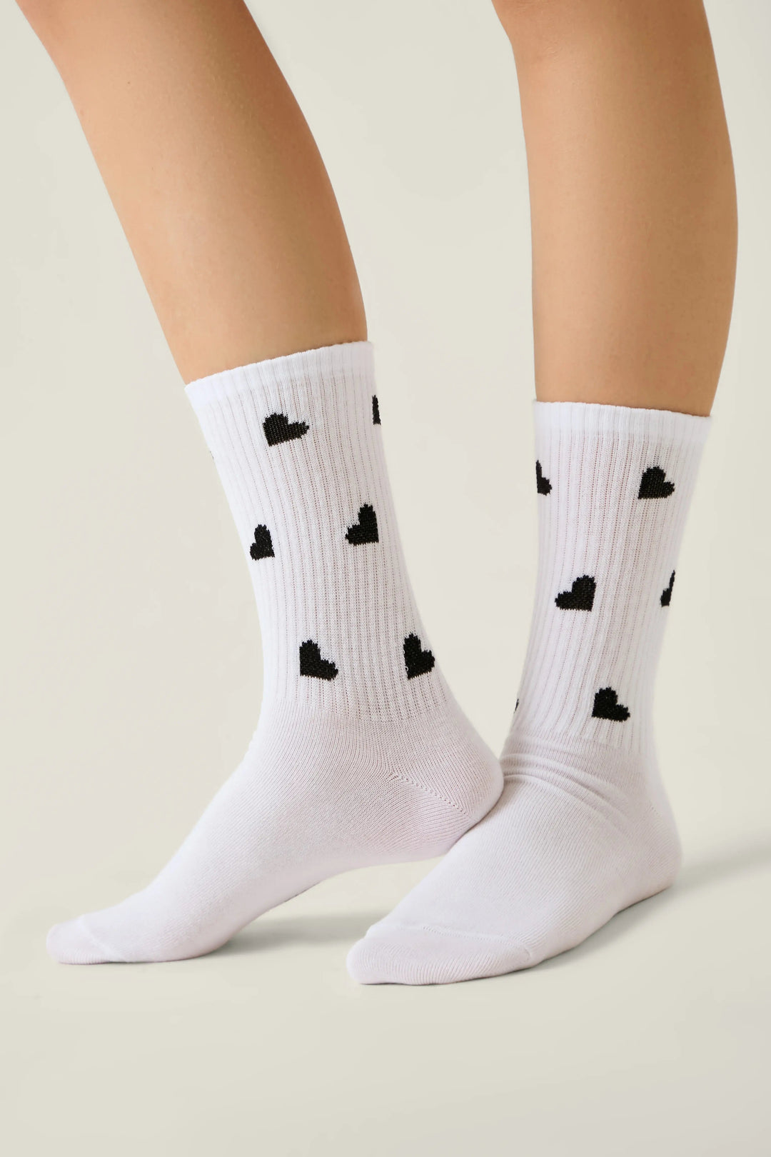White socks with black heart patterns worn by a person on a light background #color_white