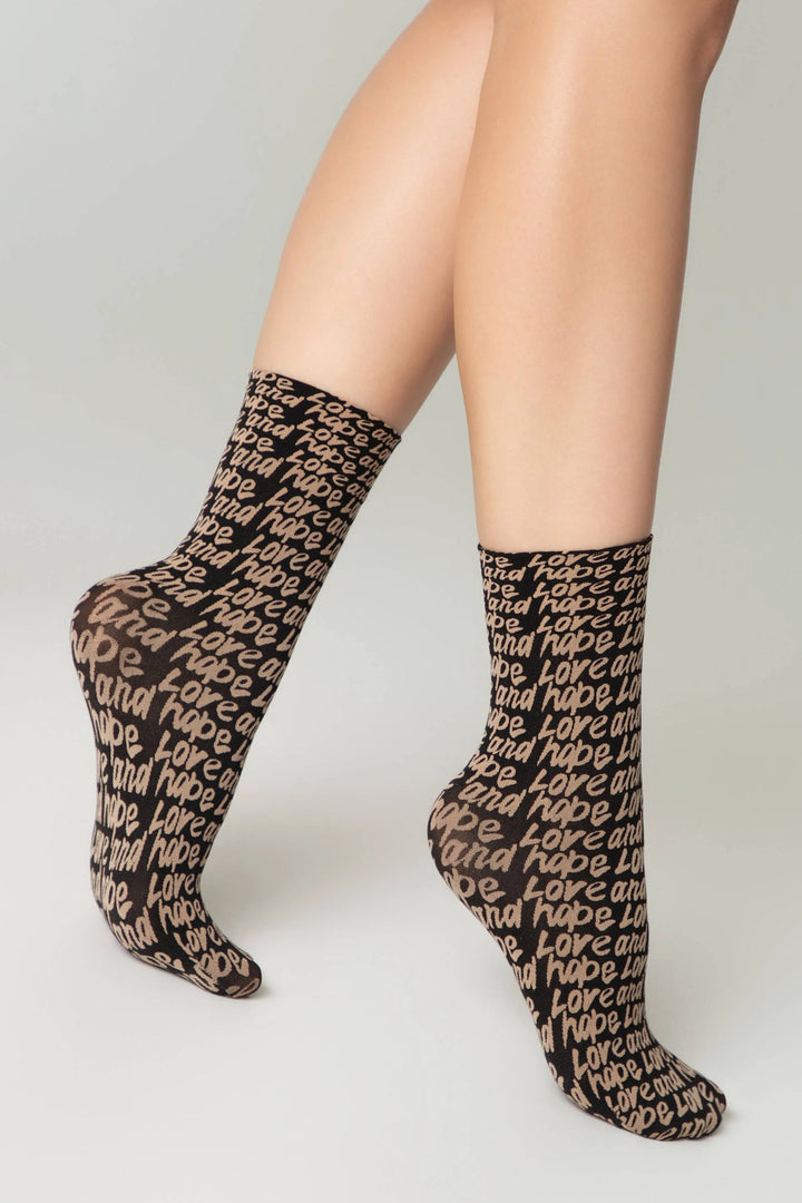 Black socks with text worn by a person on a white background #color_nero-natural
