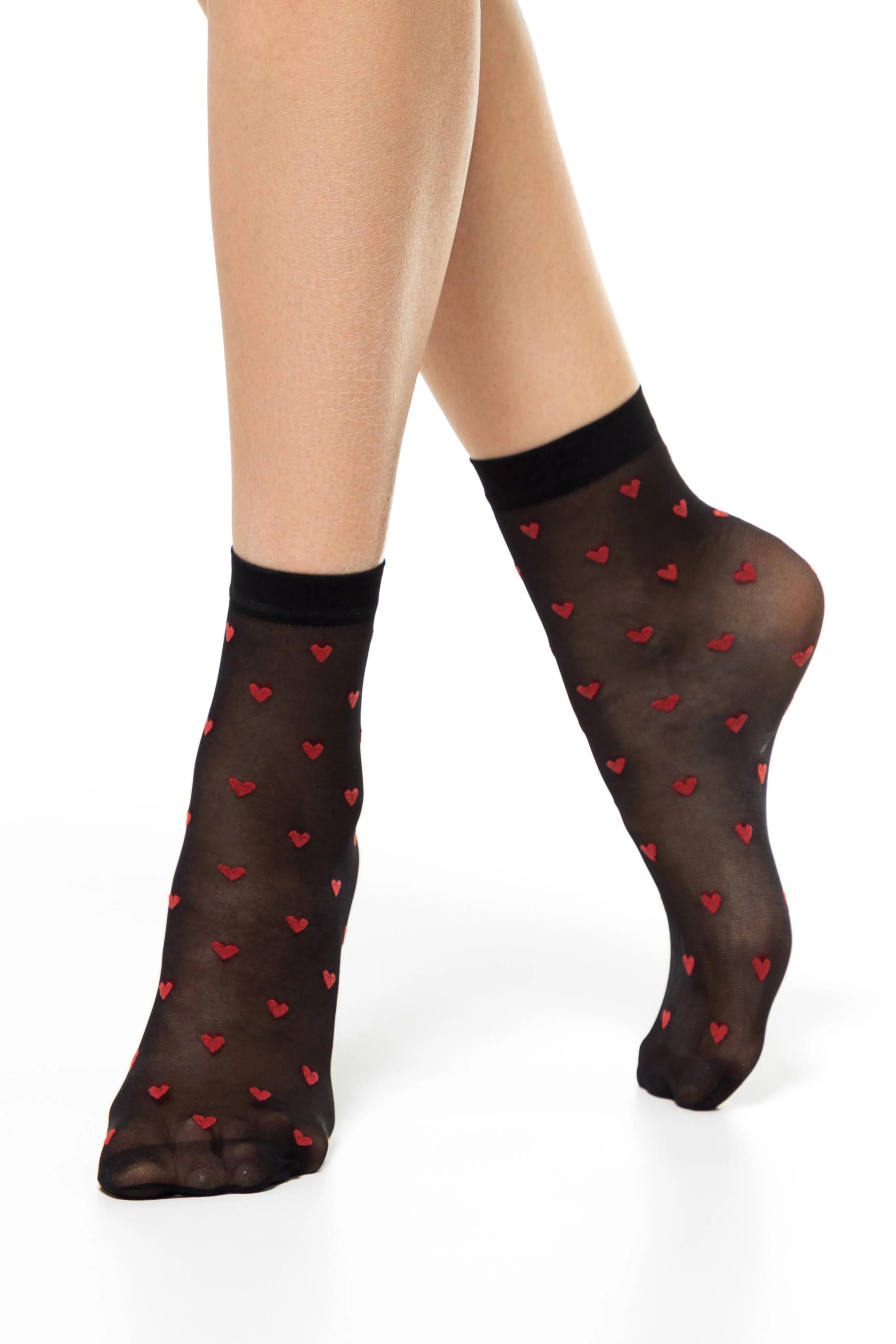 Black socks with red heart patterns worn by a person on a white background #color_nero-black