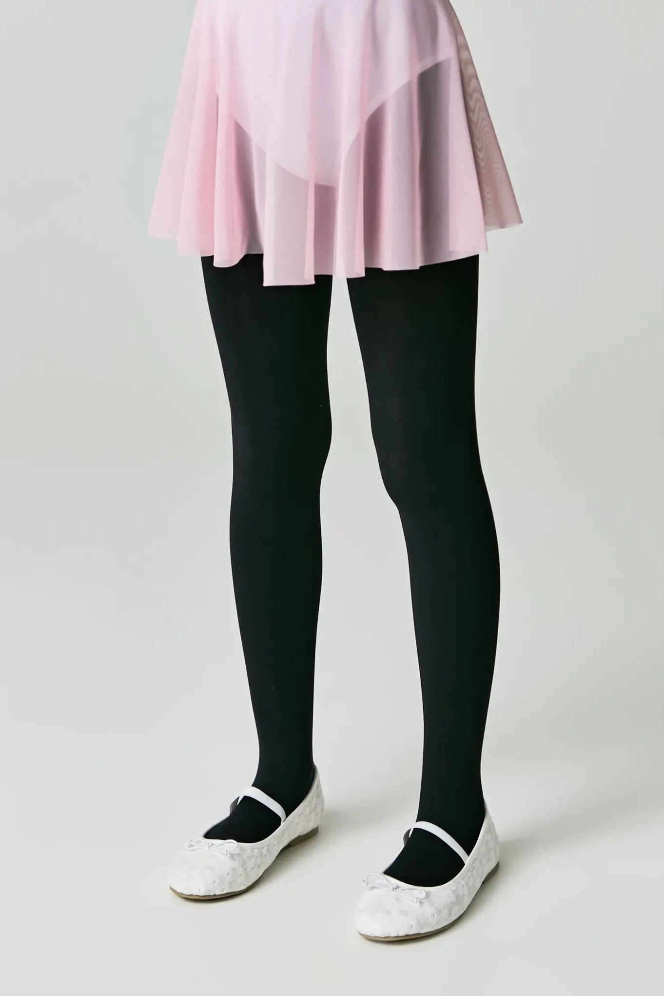 Person wearing black tights and white shoes on a plain background #color_nero-black