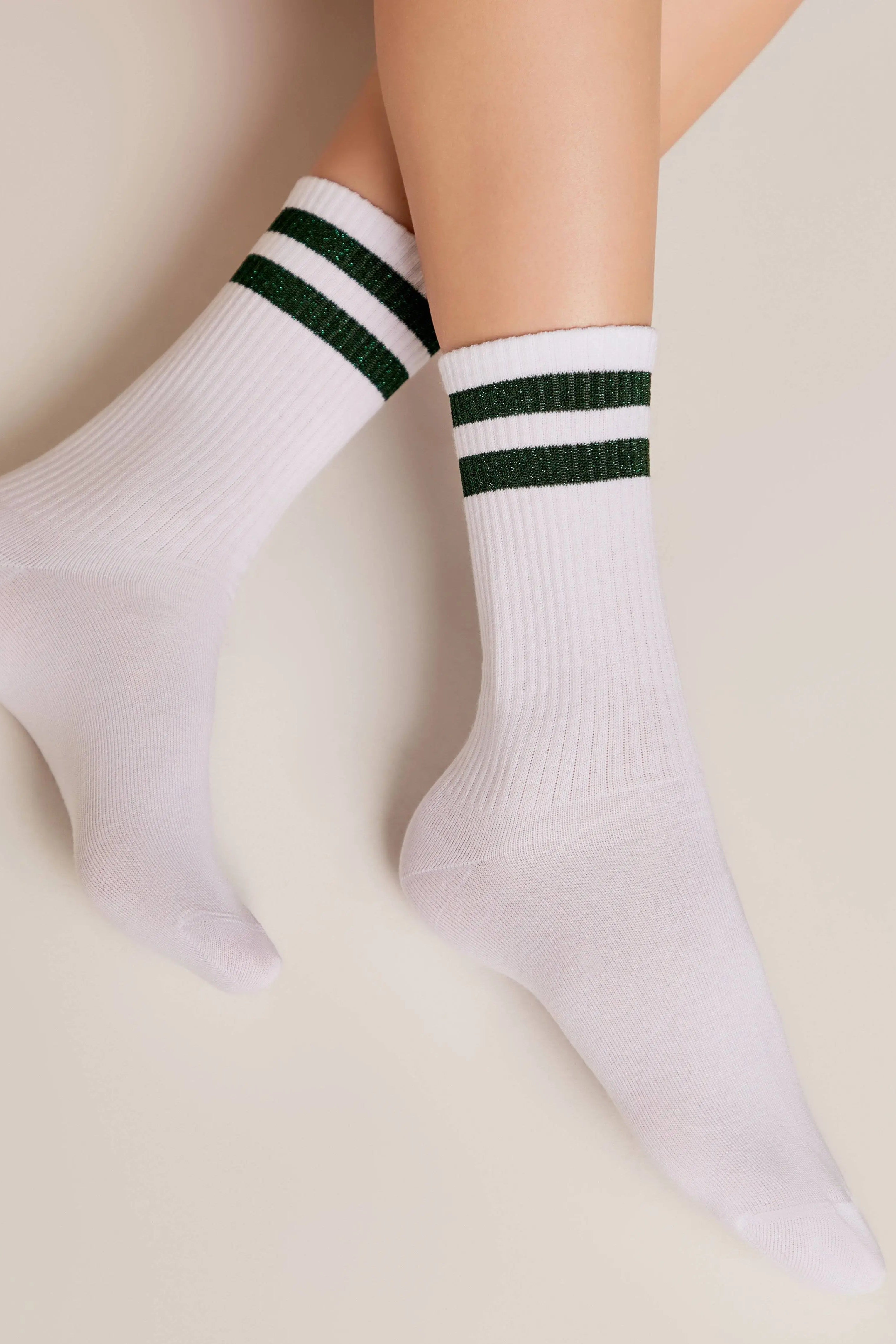White socks with green stripes worn by a person on a beige background #color_green