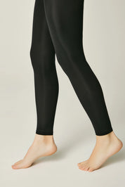 Black leggings worn by a person on a plain background #color_nero-black