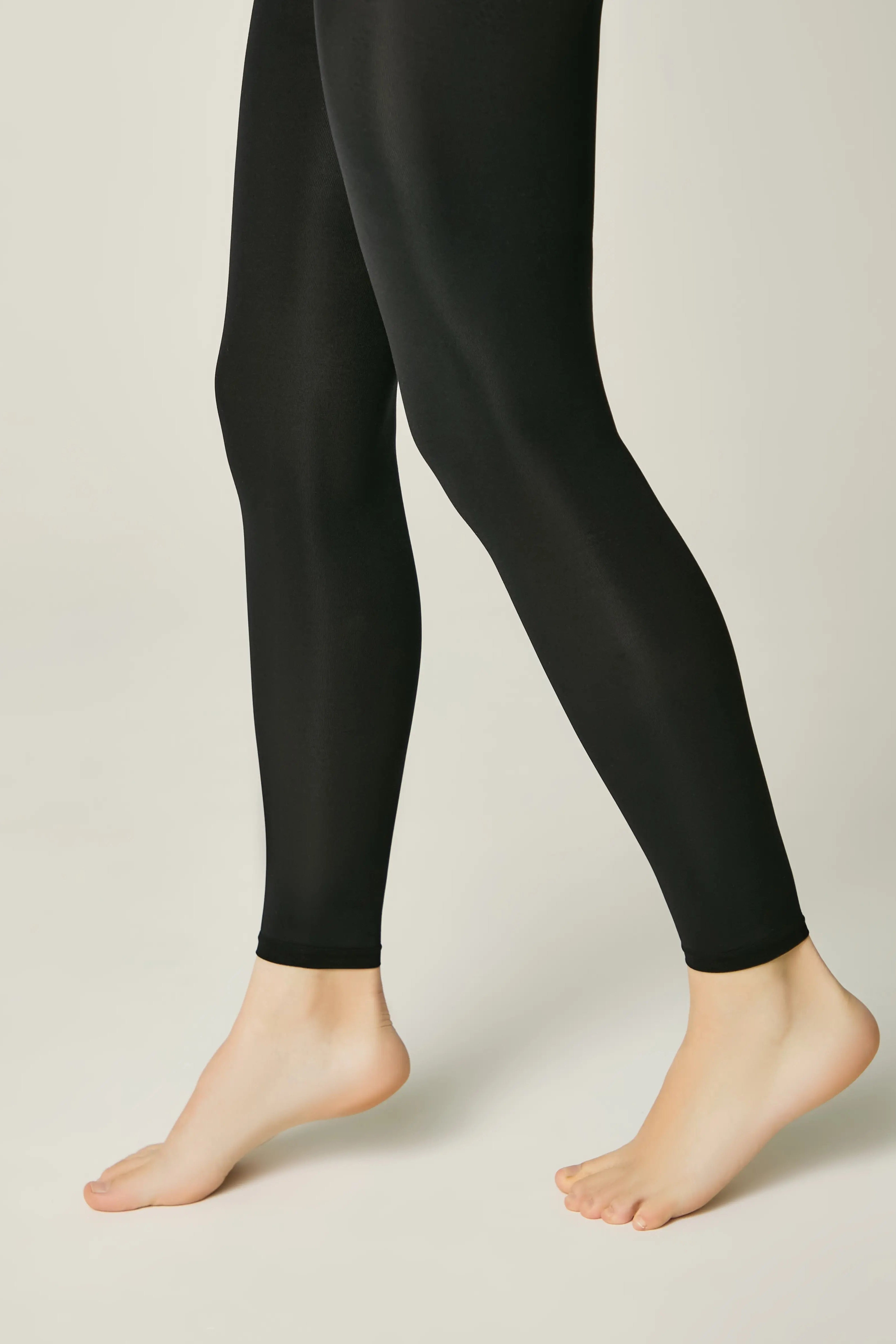 Black leggings worn by a person on a plain background #color_nero-black