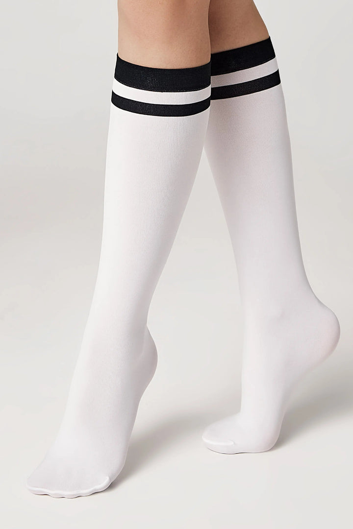 White knee-high socks with black stripes worn by a person on a light gray background