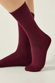 Maroon socks worn by a person on a light beige background #color_dark-bordo