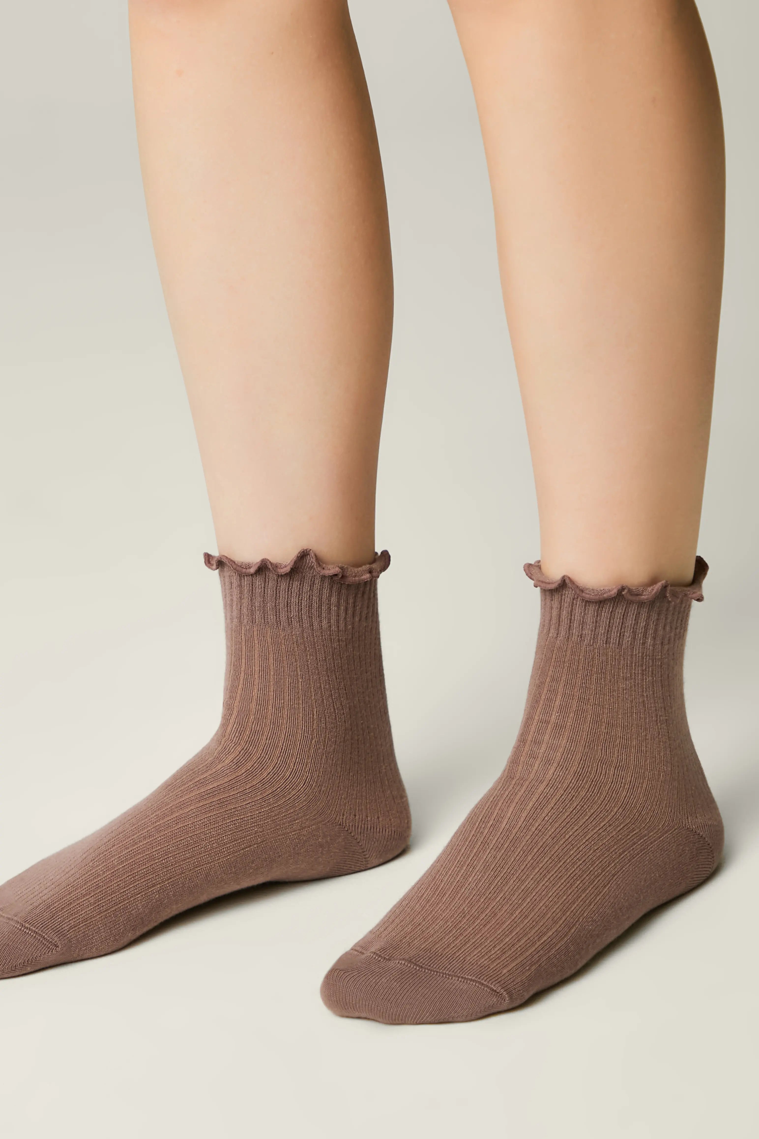 Brown socks with ruffled top worn by a person on a neutral background #color_coffee