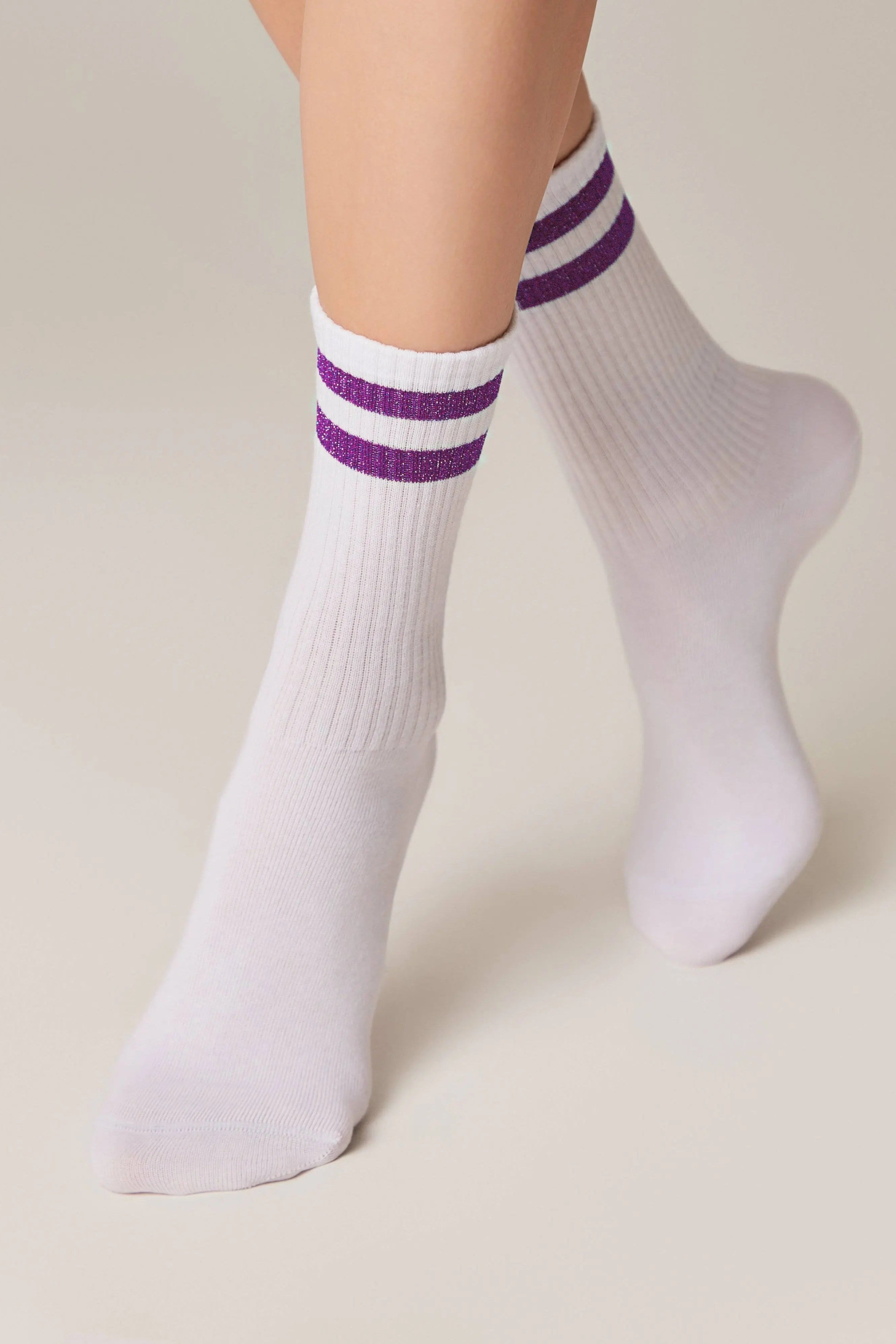 White socks with purple stripes worn by a person on a beige background #color_lilac
