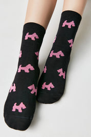 Black socks with pink dog patterns worn by a person on a light gray background #color_black