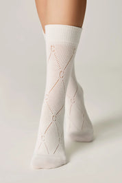 White socks with a subtle pattern worn by a person on a light gray background #color_milk