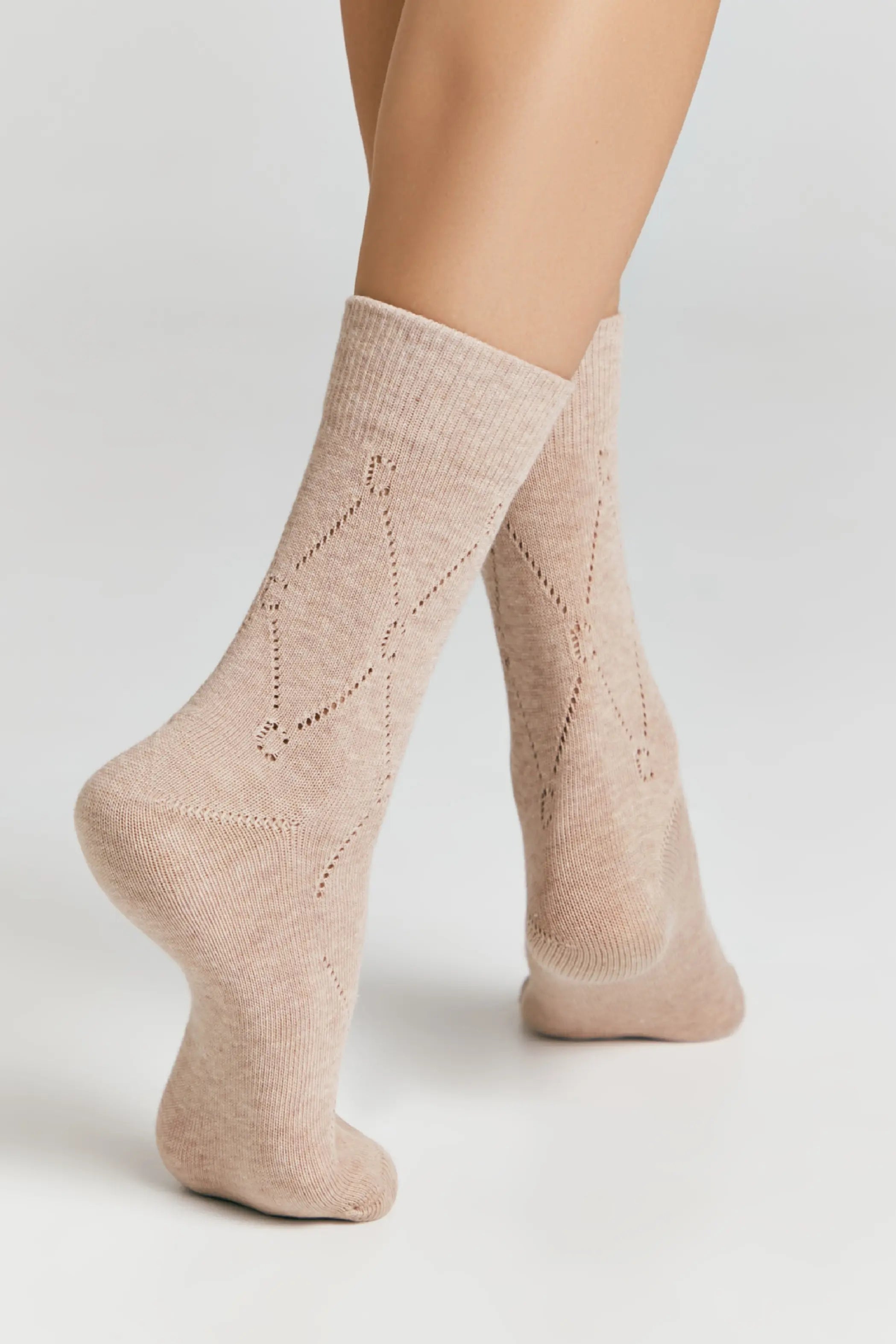 Beige socks with subtle pattern worn by a person on a light gray background #color_beige
