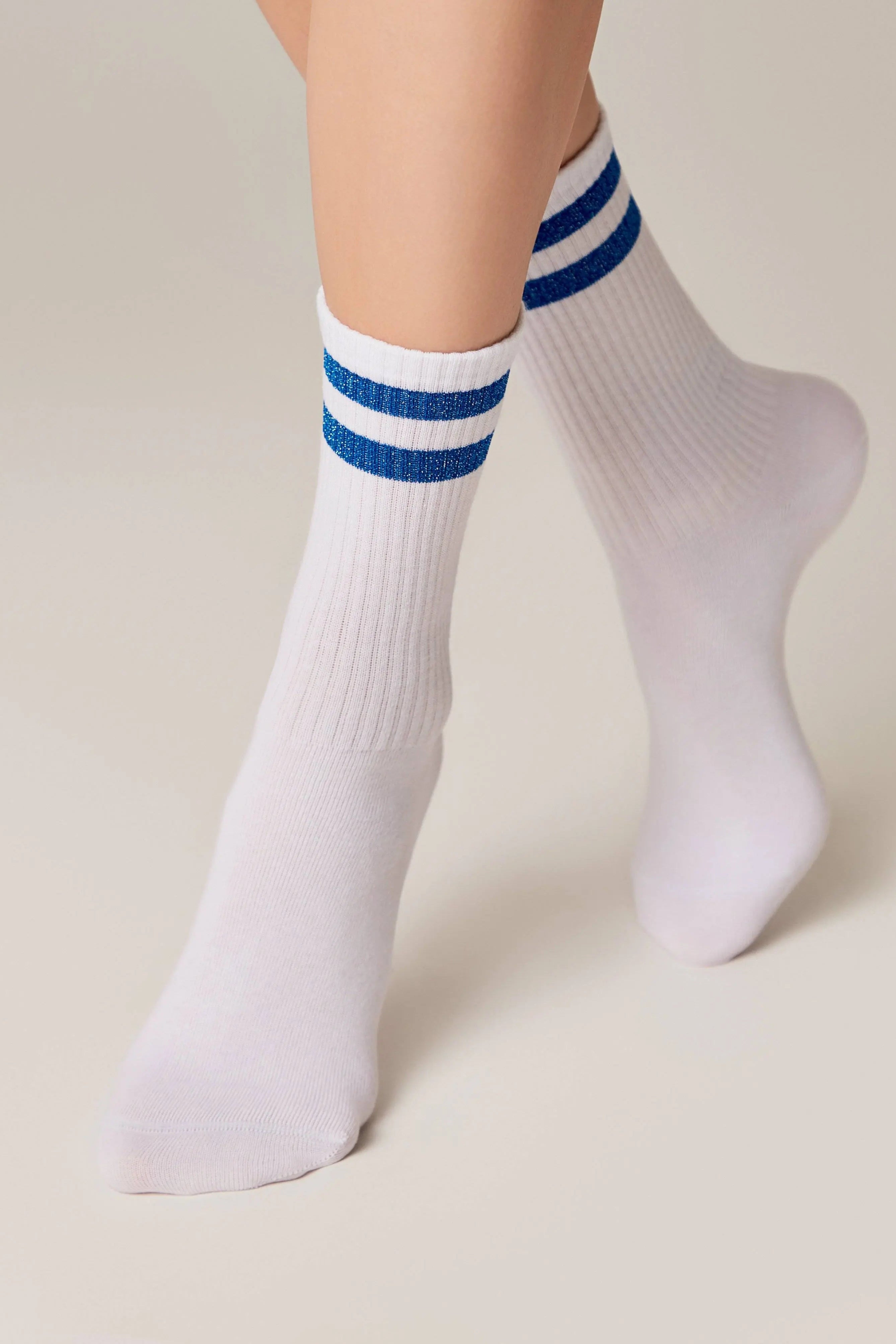 White socks with blue stripes worn by a person on a beige background #color_blue