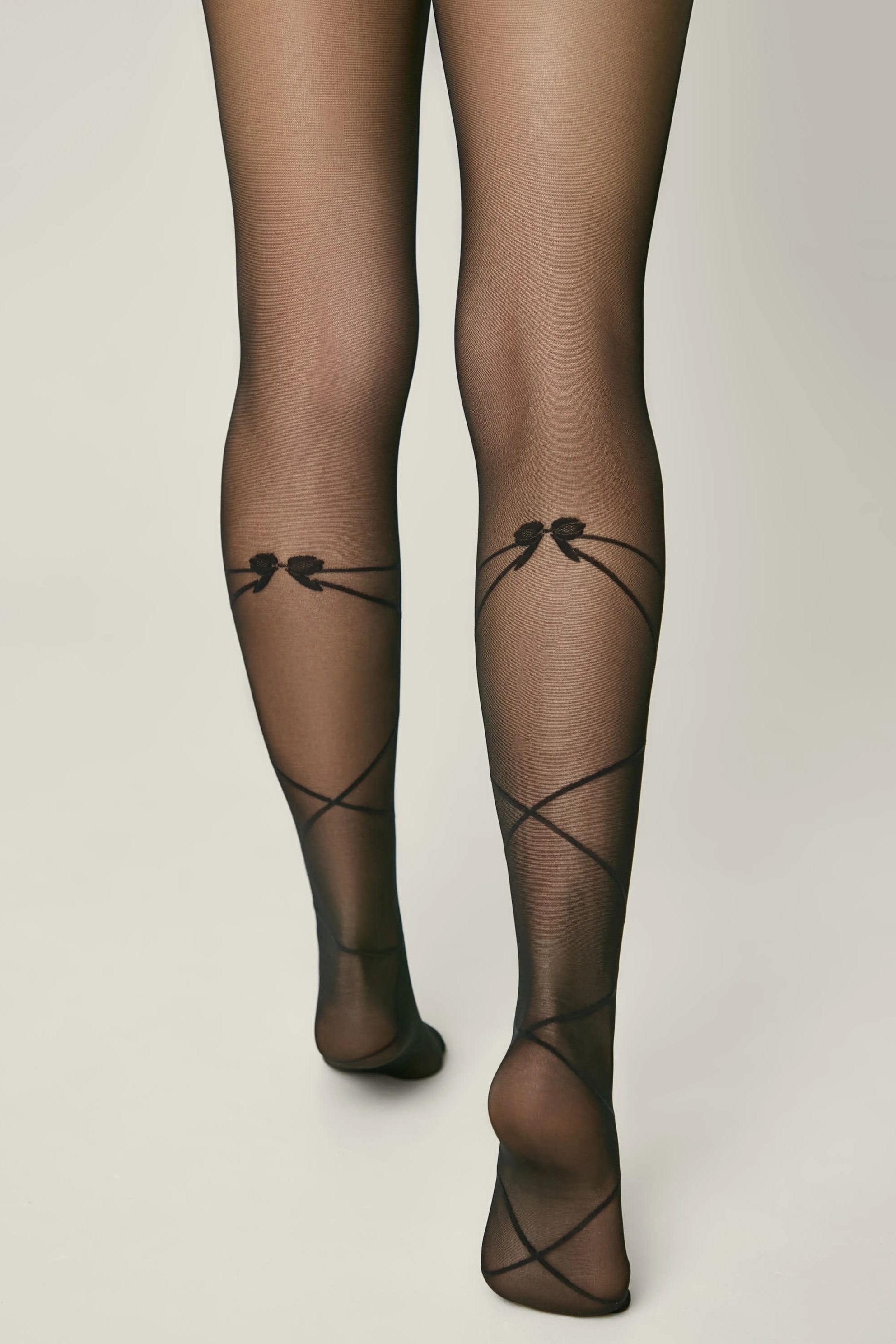 Black sheer stockings with decorative bows on a neutral background #color_nero-black