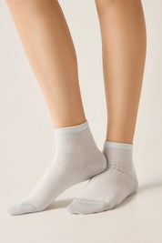 Gray ankle socks worn by a person on a light beige background #color_light-gray