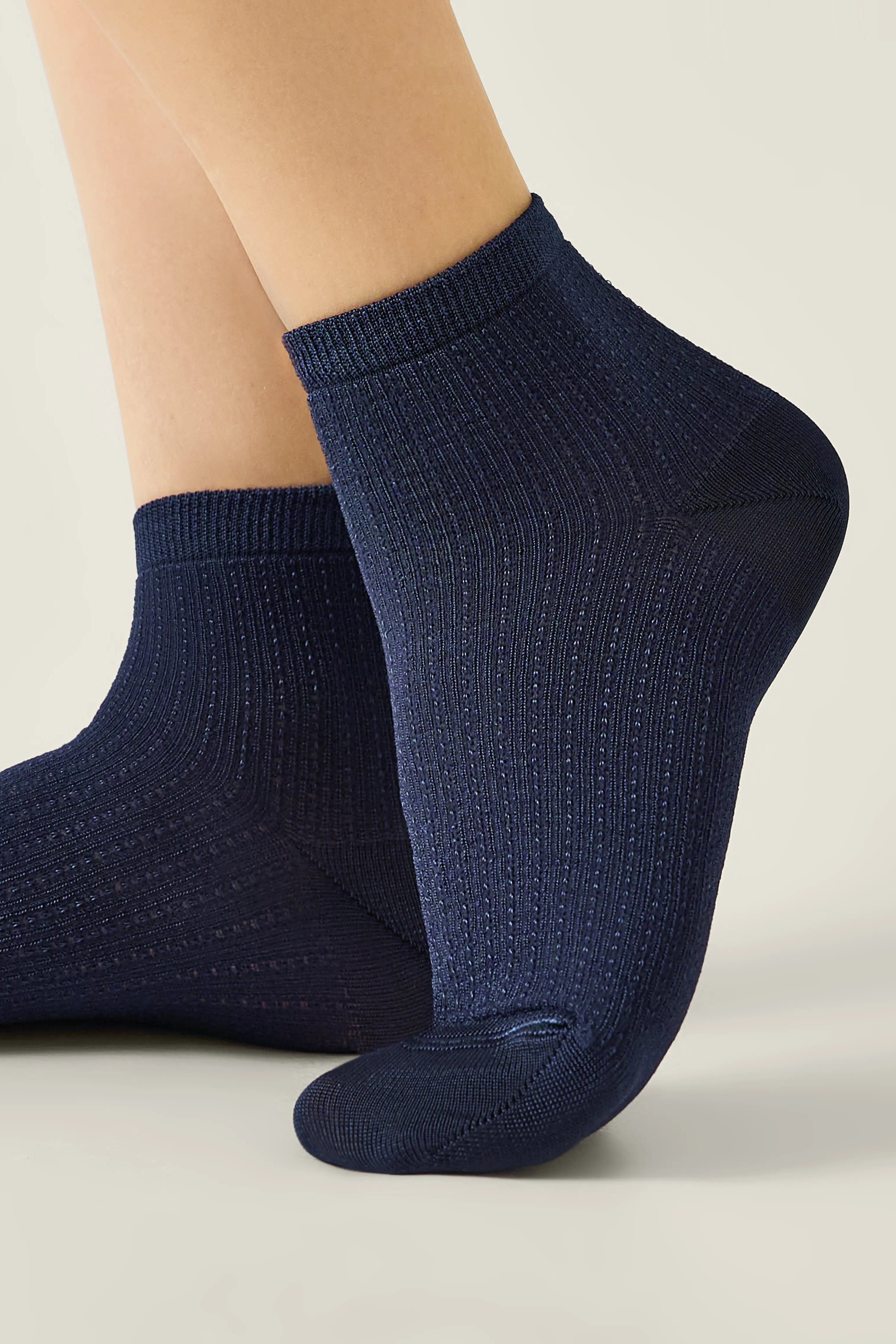 Navy blue ankle socks worn by a person on a light gray background #color_dark-blue