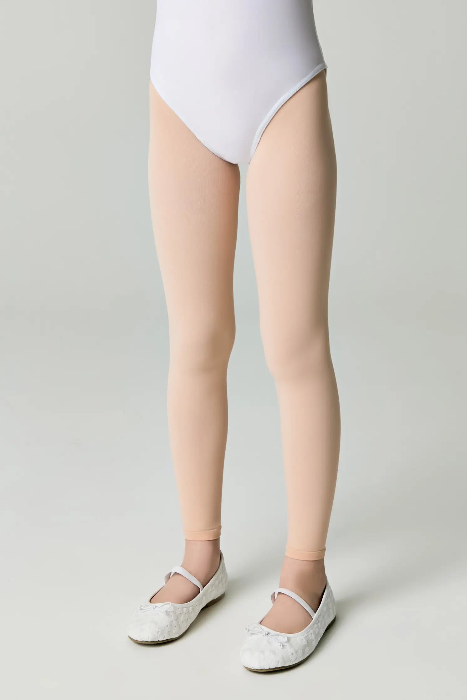 Person wearing a white bodysuit and beige tights on a plain background #color_pink-ballet