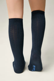 Navy knee-high socks with a subtle pattern worn by a person on a light gray background #color_dark-blue