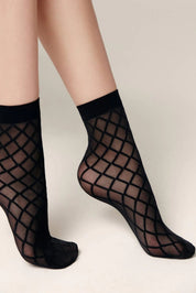 Black fishnet socks worn by a person on a neutral background #color_nero-black