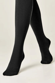 Black tights worn by a person on a plain background
