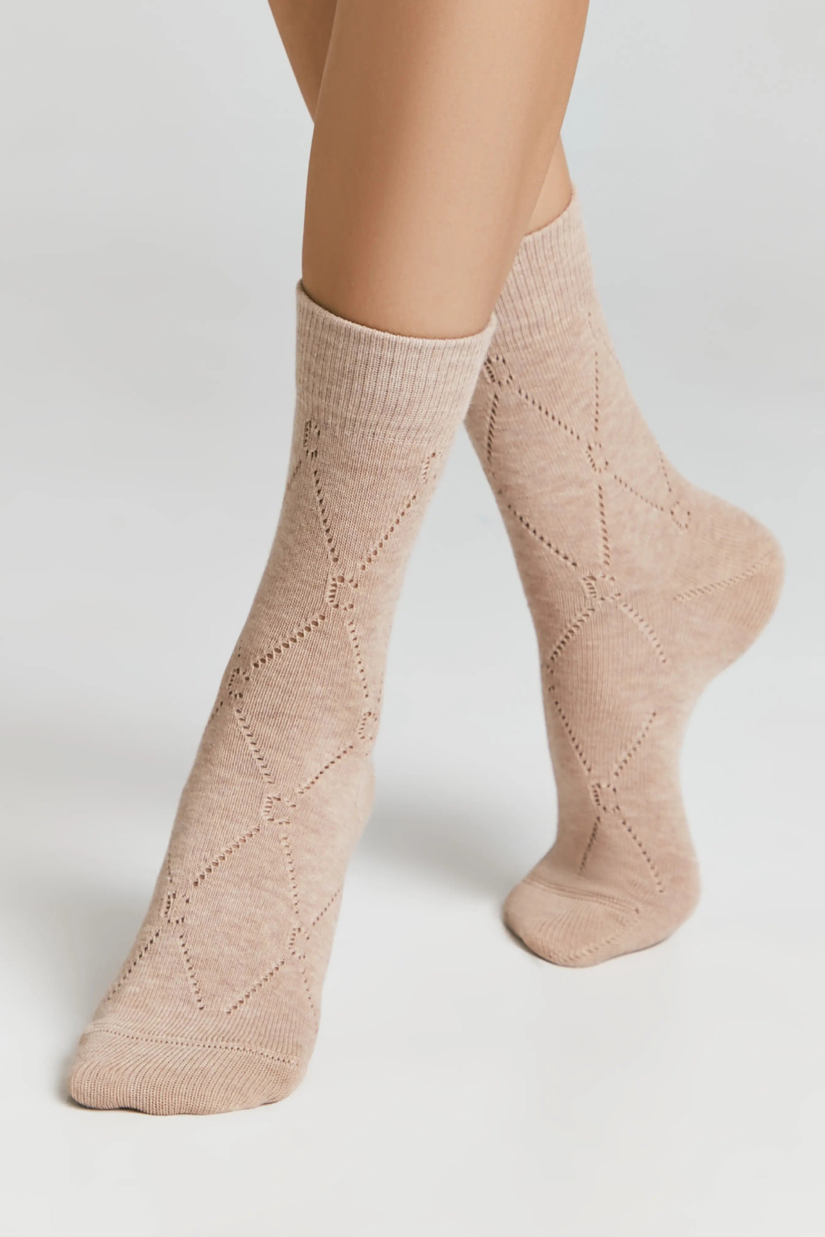 Beige patterned socks worn by a person on a light gray background #color_beige