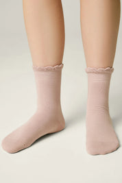 Pink socks with lace trim worn by a person on a neutral background #color_ash-pink