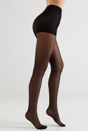 A model's legs wearing sheer black tights, shown from a side profile against a light gray studio background.