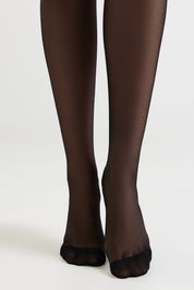 Black toeless hosiery shown on a model's legs against a plain light gray studio background.