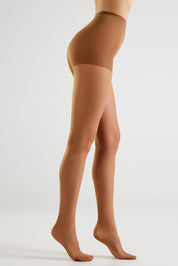 Side view of a model wearing sheer, skin-toned hosiery with a high waistband, shown against a plain light gray studio background.