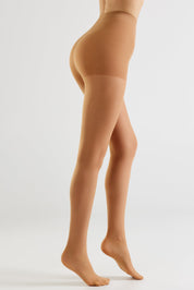 A model's lower body shown from the waist down, wearing sheer, skin-toned hosiery against a clean, light gray studio background.
