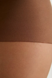 Close-up of a sheer brown hosiery leg section over skin, showing the fine knit texture and color.