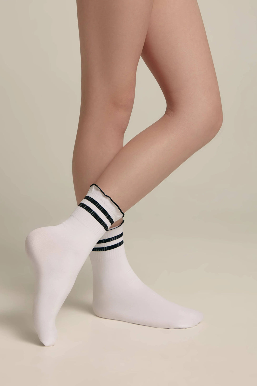 White socks with black stripes worn by a person on a beige background