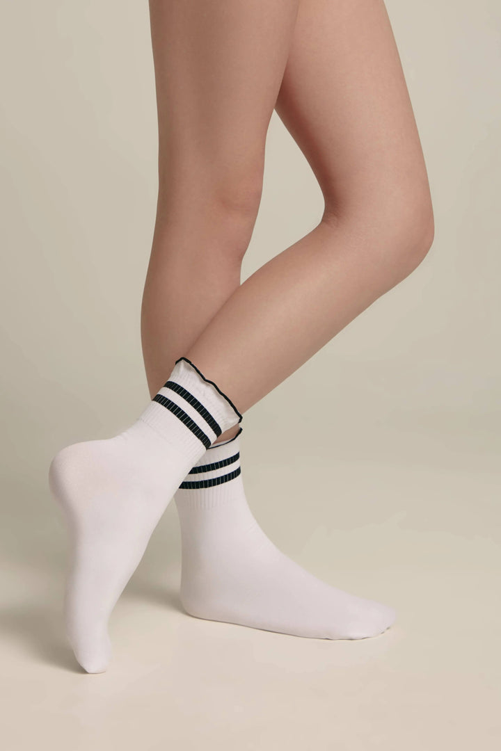 White socks with black stripes worn by a person on a beige background