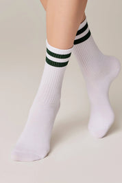 White socks with green stripes worn by a person on a beige background #color_green