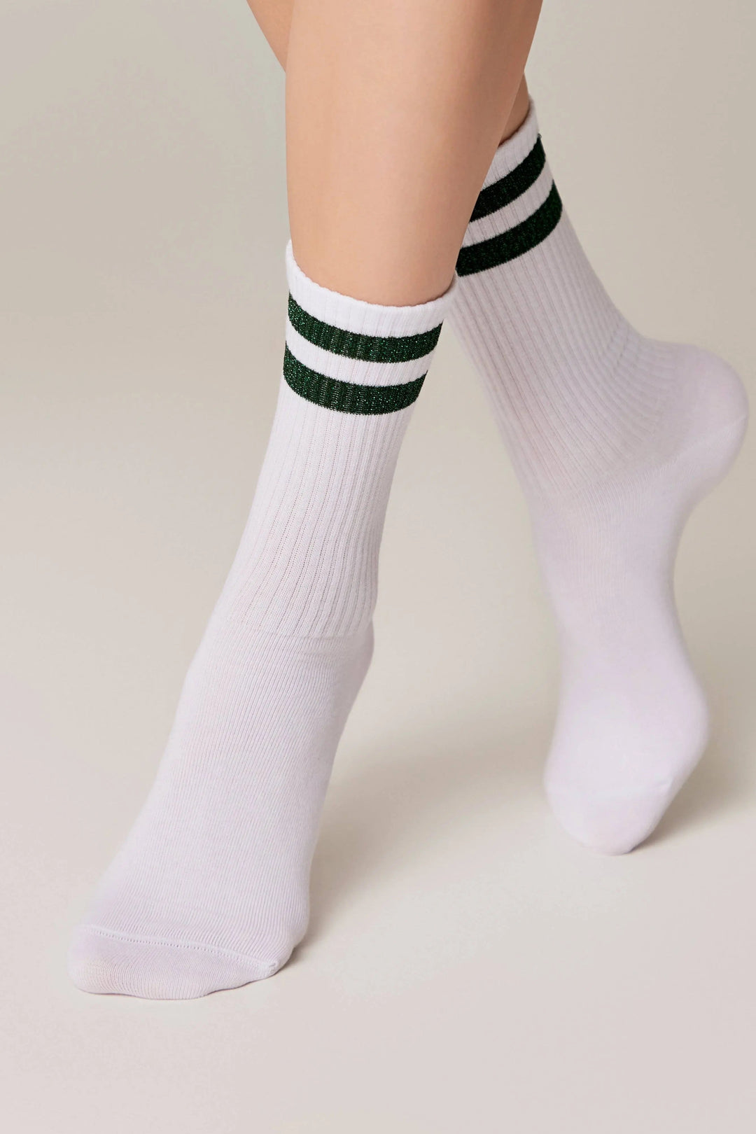 White socks with green stripes worn by a person on a beige background #color_green