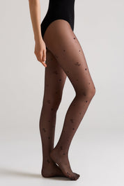 Brown tights with black heart patterns worn by a person on a light gray background