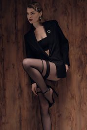Woman in black outfit with stockings against a wooden background