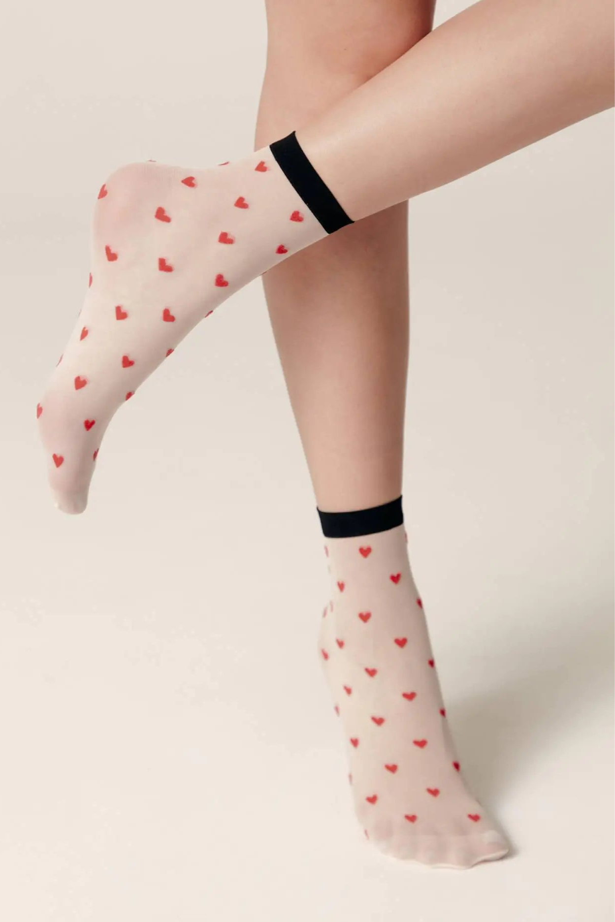 Sheer socks with heart pattern worn by a person on a plain background #color_panna