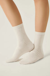 White socks worn by a person on a light gray background #color_milky