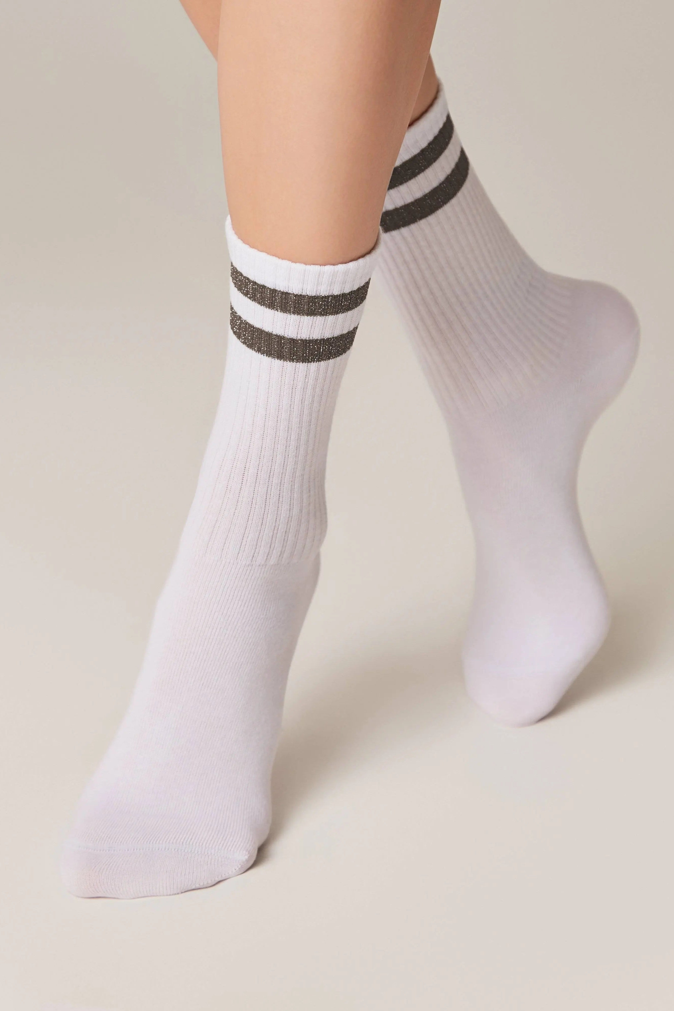 White socks with black and gray stripes worn by a person on a beige background #color_gray