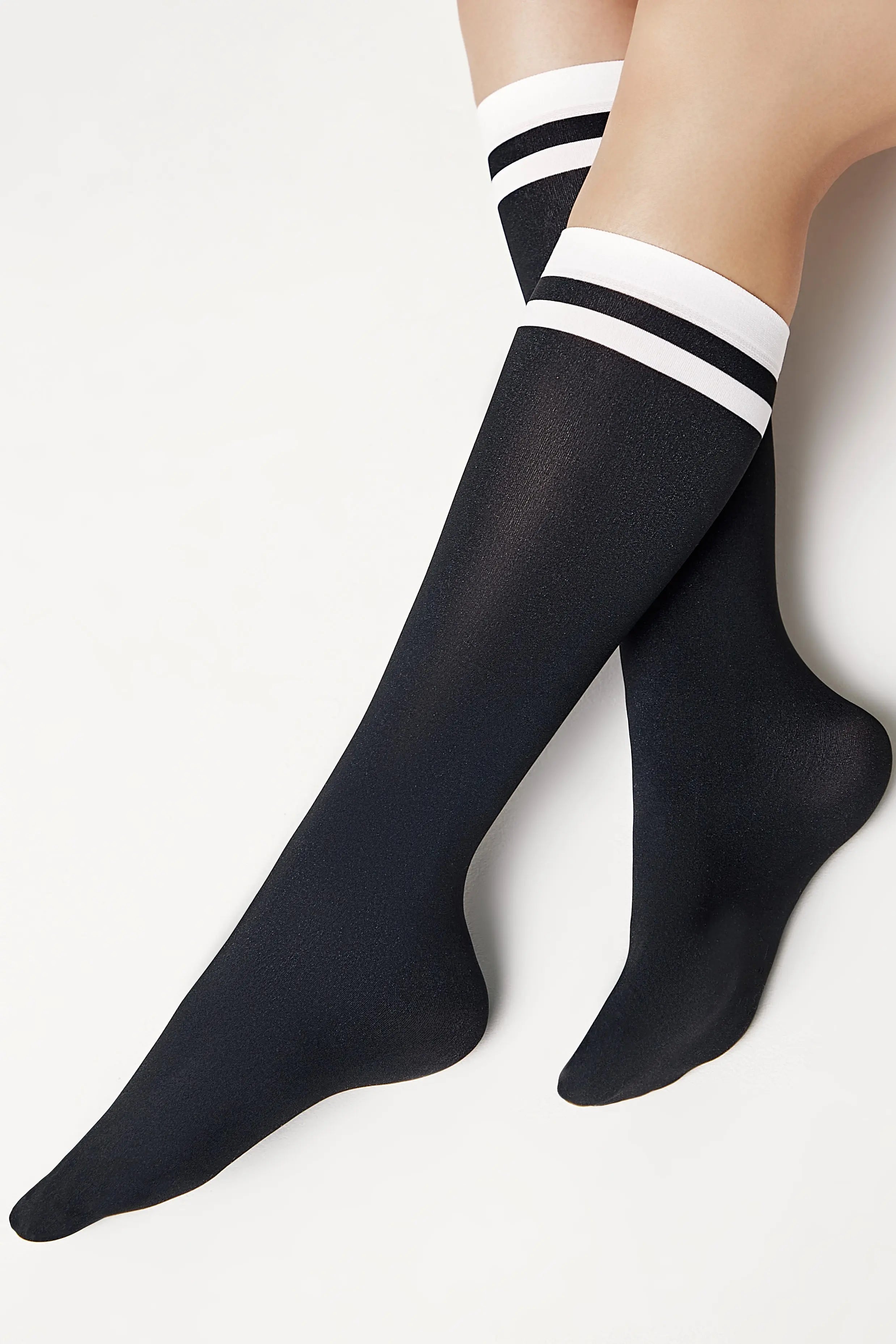 Black knee-high socks with white stripes on a light gray background