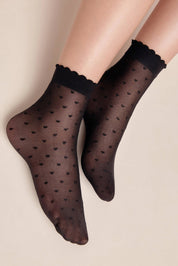 Black patterned socks with scalloped edges worn by a person on a beige background #color_nero-black