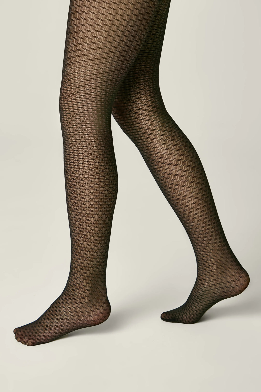 Black fishnet tights worn by a person on a light gray background #color_nero-black