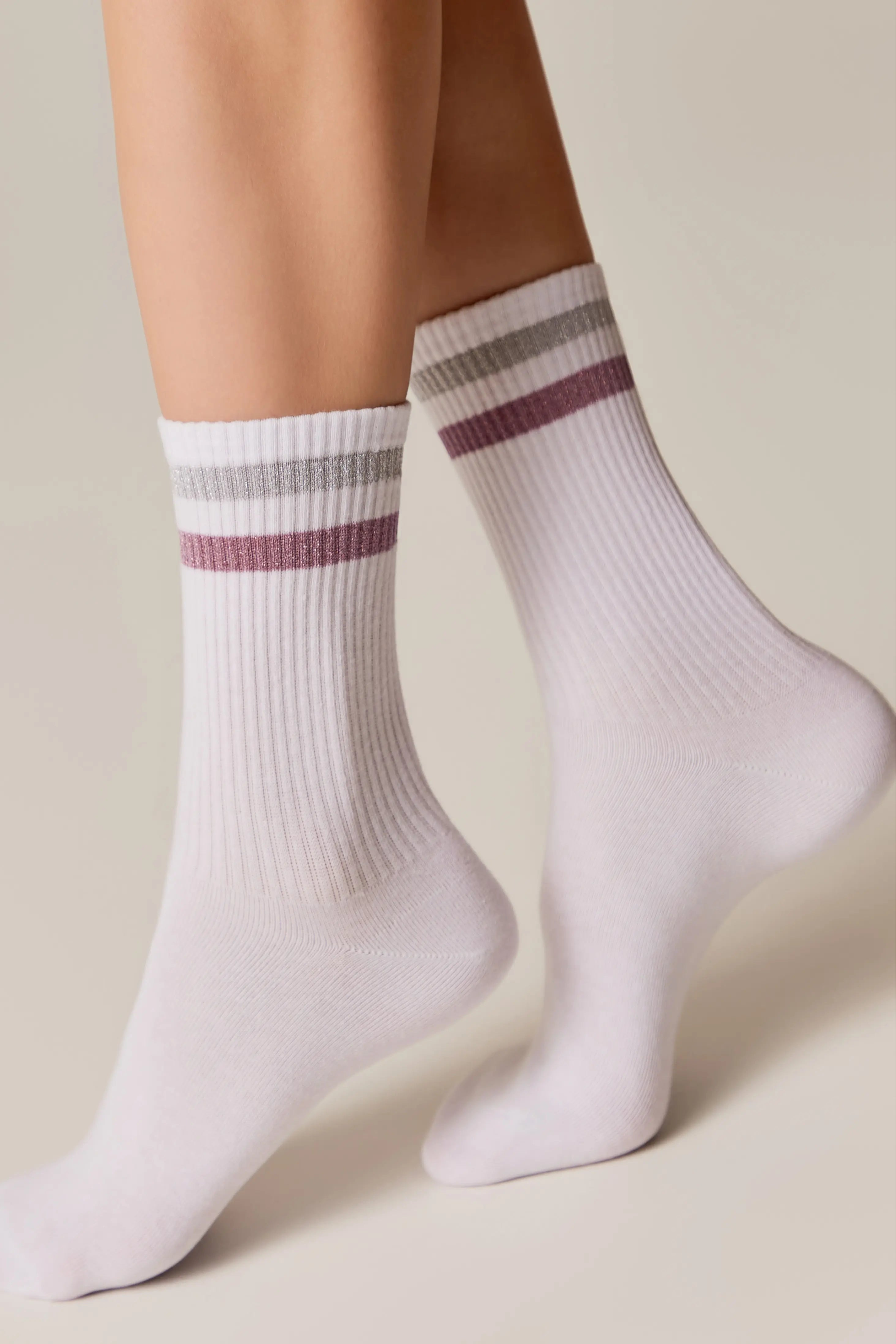 White socks with purple stripes worn by a person on a beige background #color_light-gray