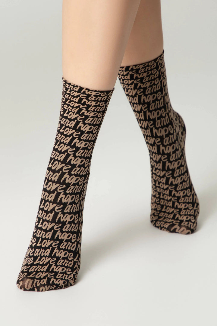 Black socks with text pattern worn by a person on a light gray background #color_nero-natural