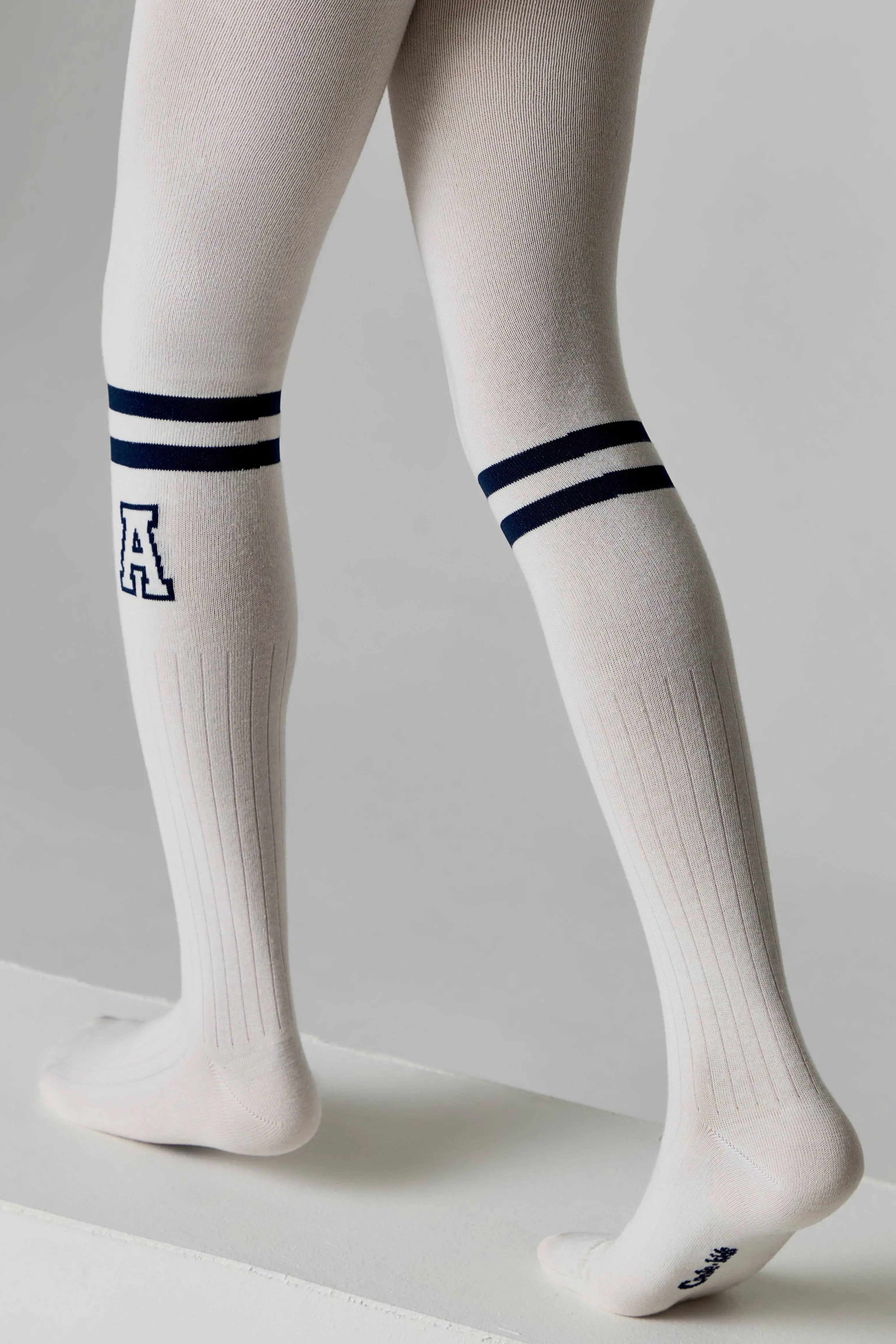 White knee-high socks with blue stripes and a letter 'A' on a gray background