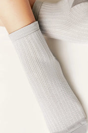 Light gray sock worn by a person on a neutral background #color_gray