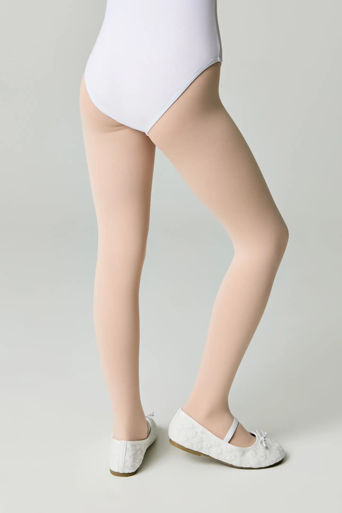 Person wearing a white bodysuit and beige stockings on a plain background #color_pink-ballet