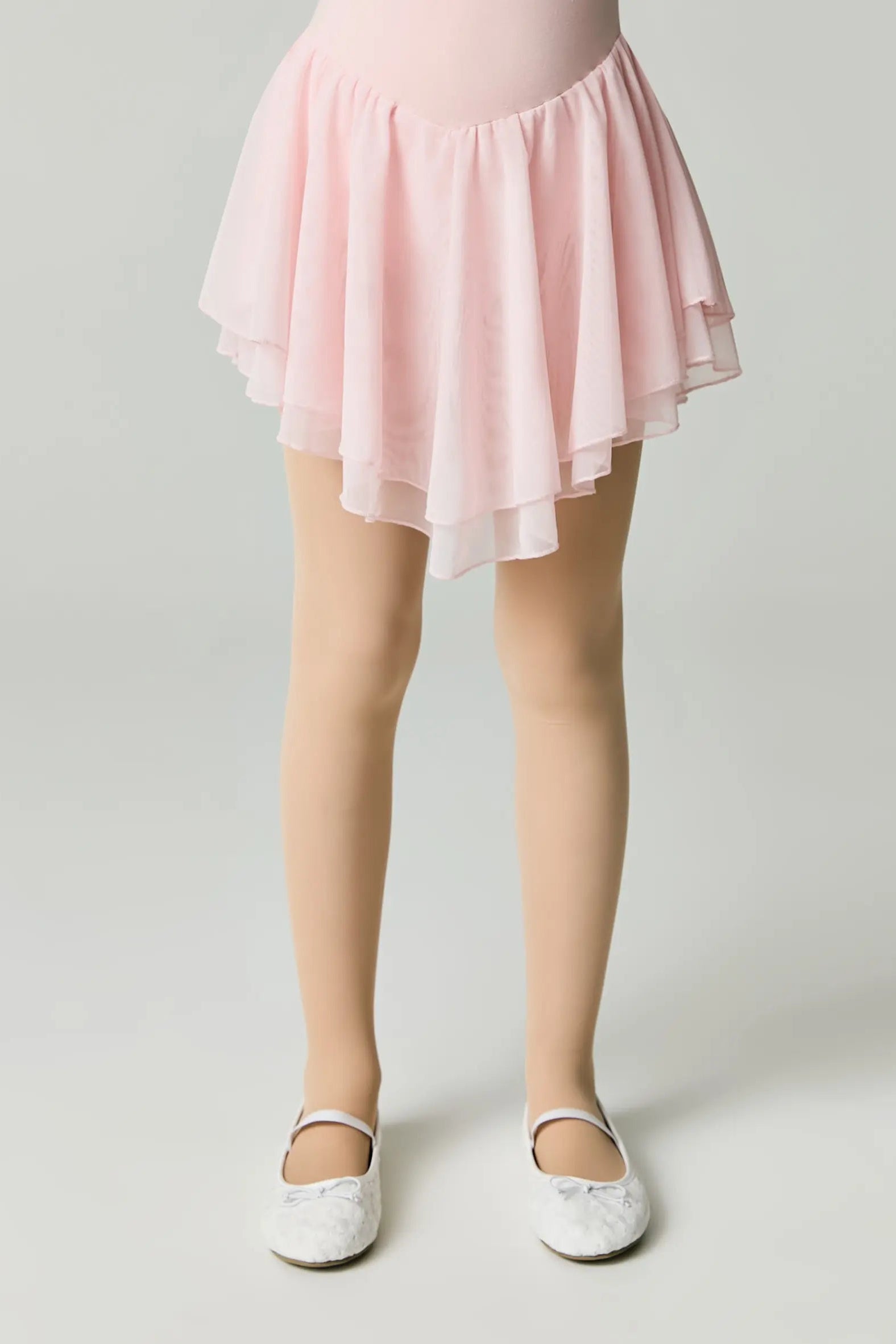 Person wearing a pink skirt and white shoes on a light gray background #color_natural-nude