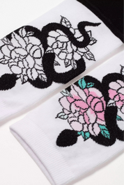 Two white socks with black snake and floral designs on a white background