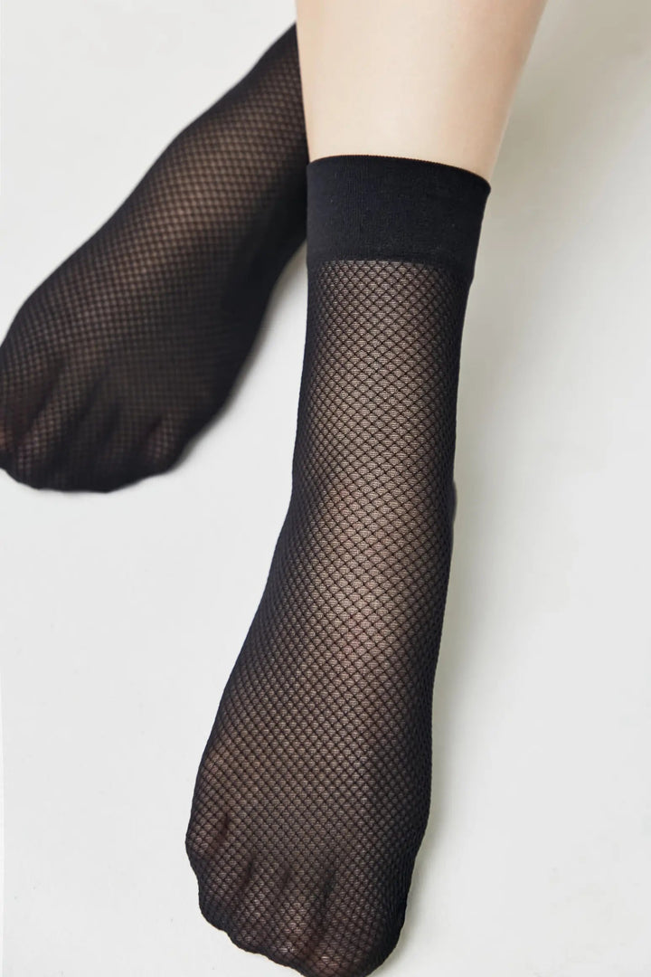 Black fishnet socks worn on a light gray background #color_nero-black